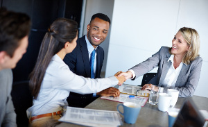 Shot of professional coworkers shaking hands during a meeting in the office