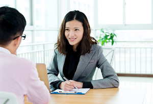 Businesswoman talking with visitor face to face at the table.